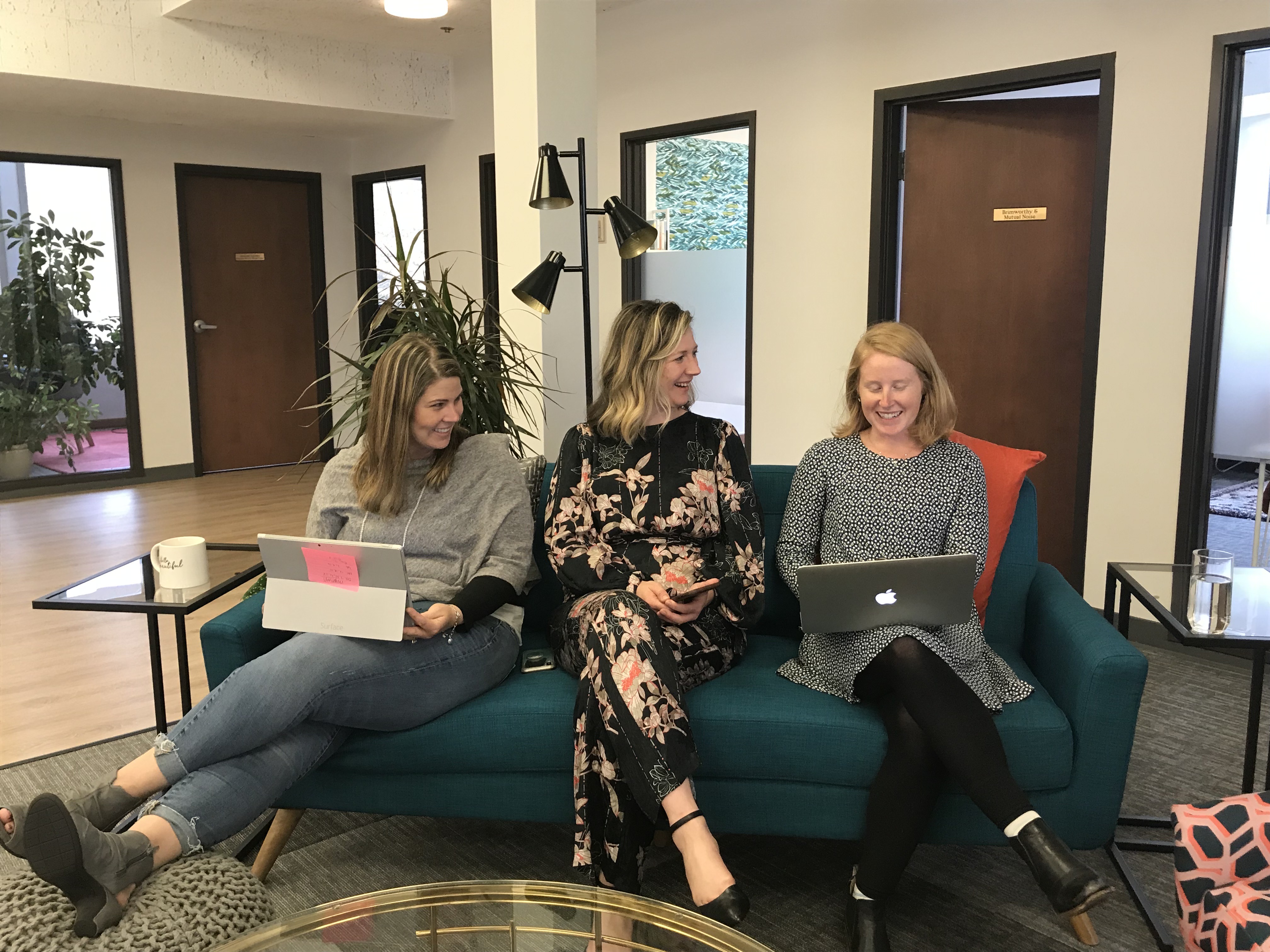 Three women sitting on a couch working on their laptops
