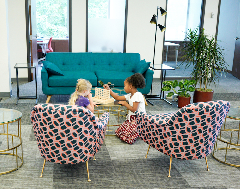A green couch and two brightly patterned chairs around a coffee table