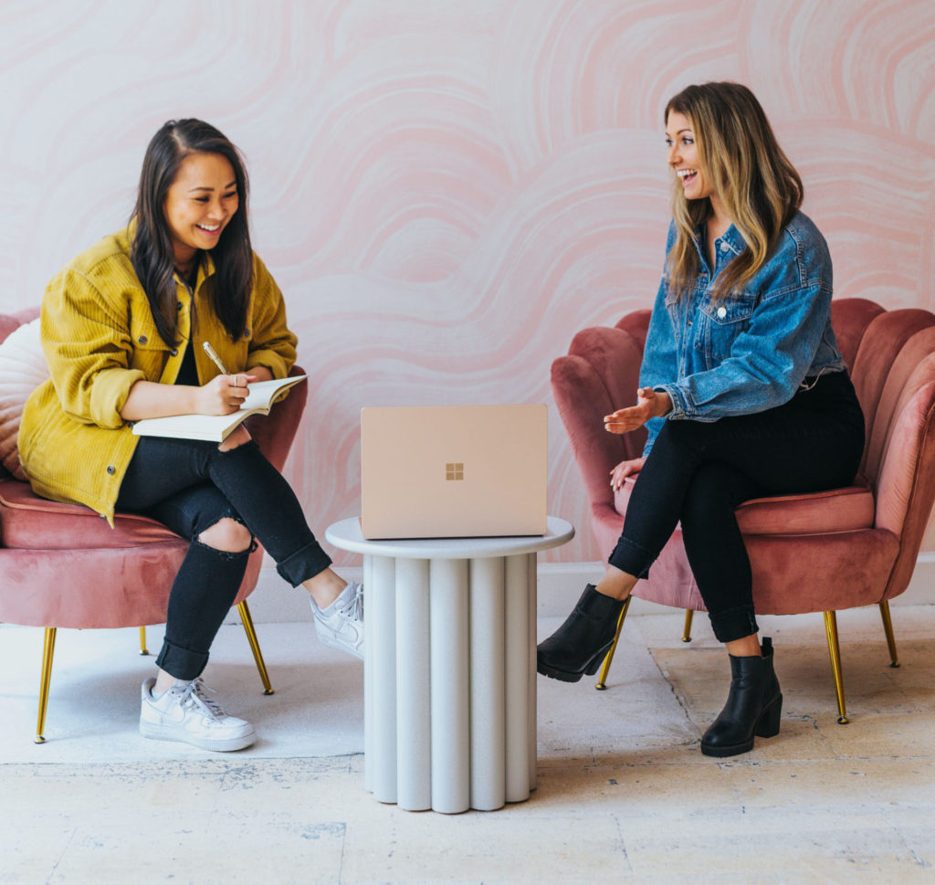 two women laughing and working in a working space