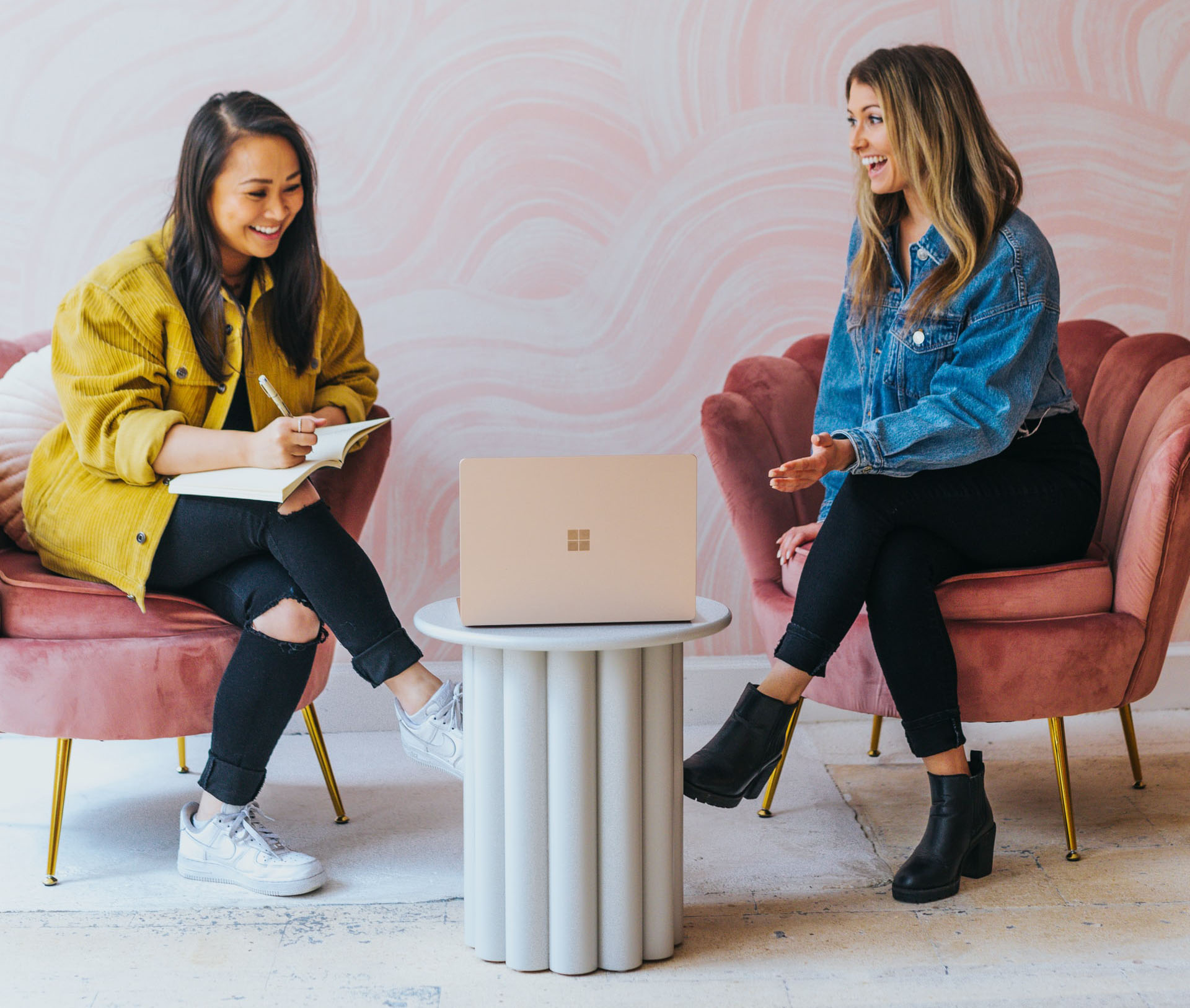 two women laughing and working in a coworking space