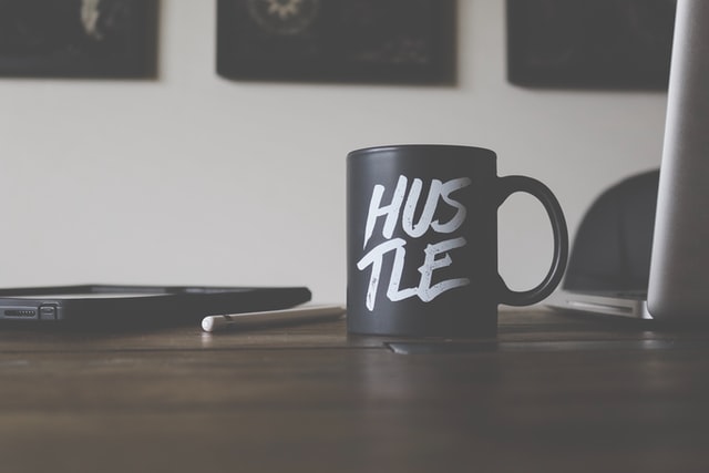 a coffee mug that says "hustle" on a desk