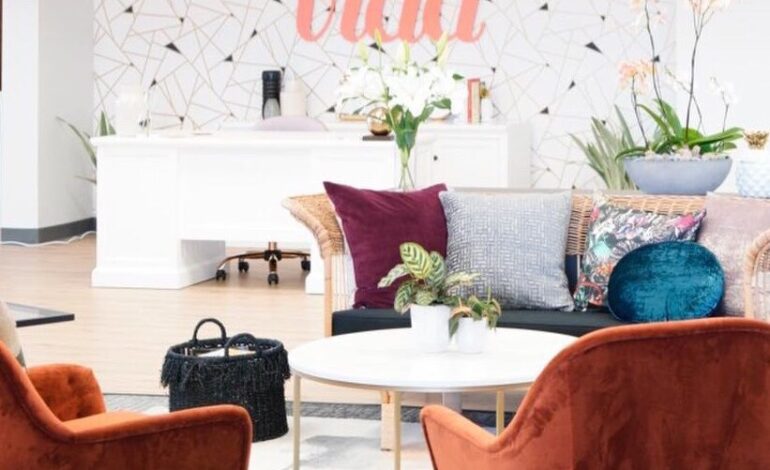 A view of the NE Portland VIDA interior, featuring low velvet chairs, a fun wall with the VIDA logo, and bright open spaces