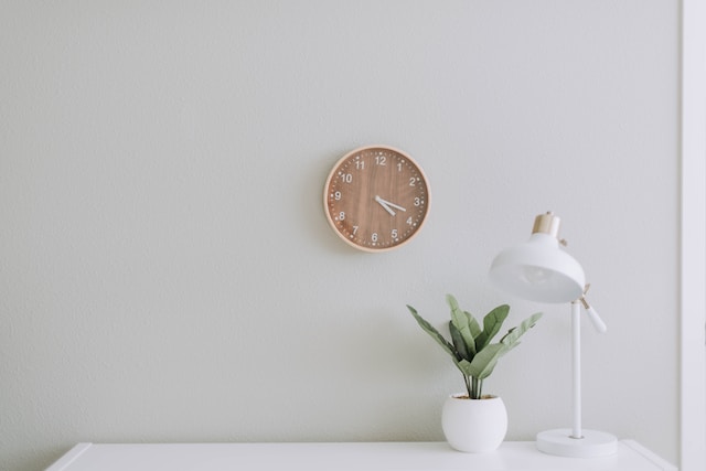 a white desk with a lamp and clock above it