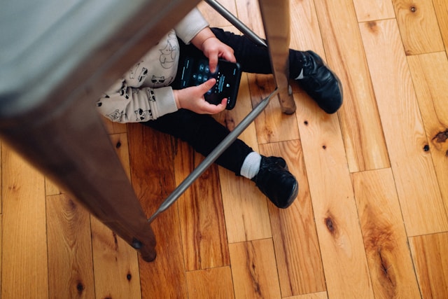 a child under an office chair holding a phone