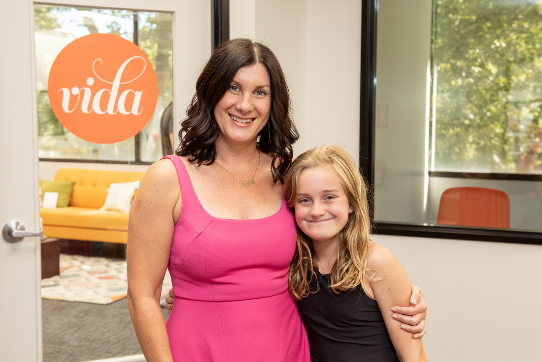 A mother and her child embracing in front of the VIDA coworking space doorway