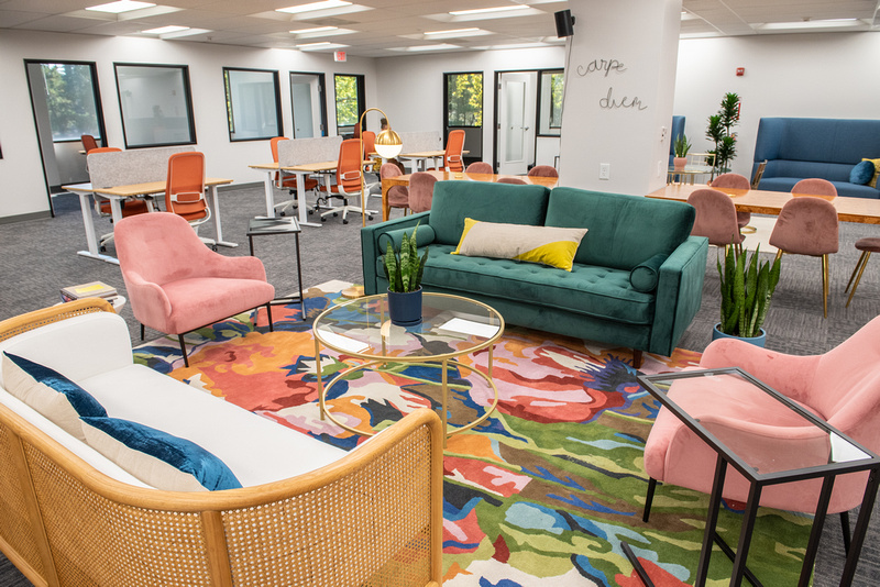A bright, colorful coworking space featuring velvet couches and comfortable chairs