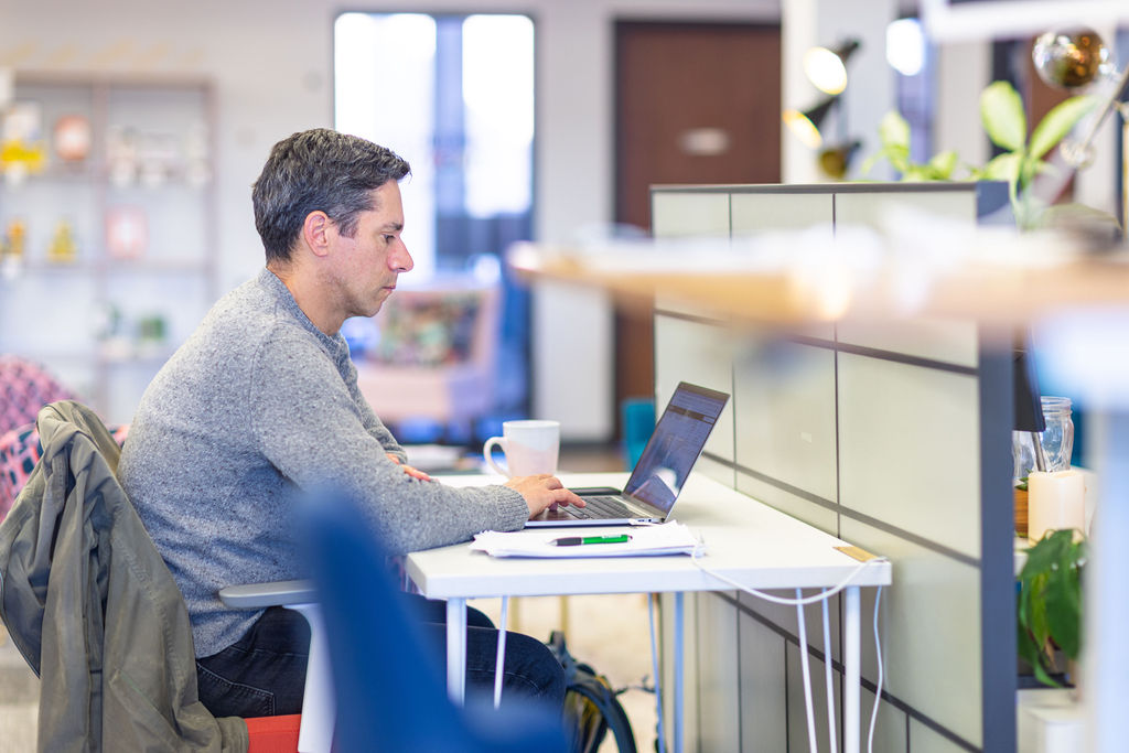 Man working on a laptop in a bright, open coworking office at VIDA Coworking in Portland