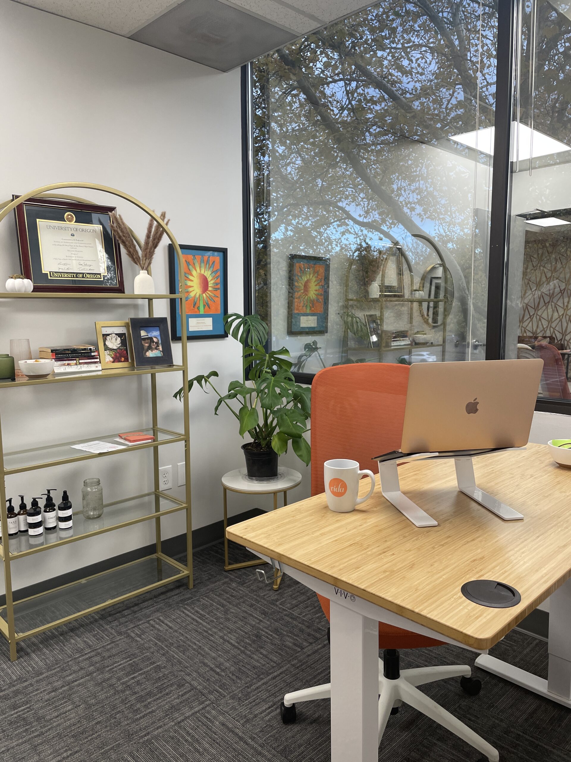 An adjustable sit/stand desk with a bookshelf full of quirky chachkies behind it