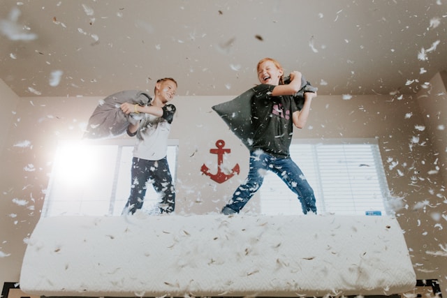 kids playing on a bed with a pillow fight