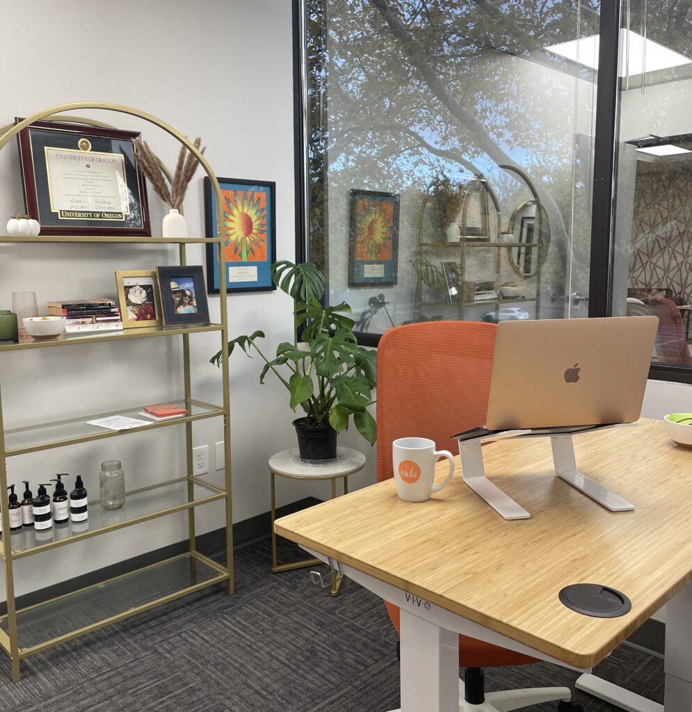An adjustable sit/stand desk with a bookshelf full of quirky chachkies behind it